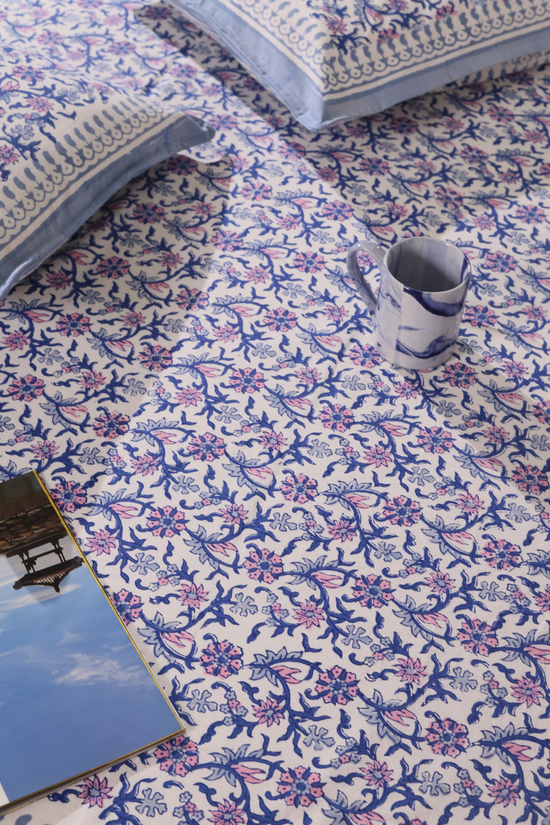 Blue and purple floral bedsheet with a mug