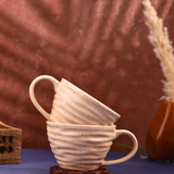 Two twirl coffee mugs on wooden surface