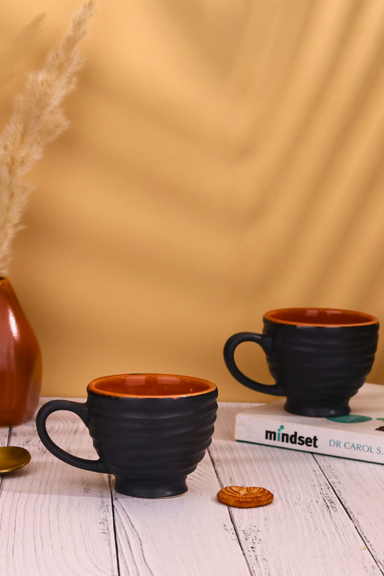 Two tea cups black colored with book