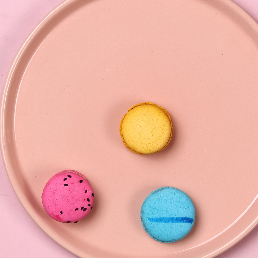 Yellow, pink, and blue macarons in pink platter