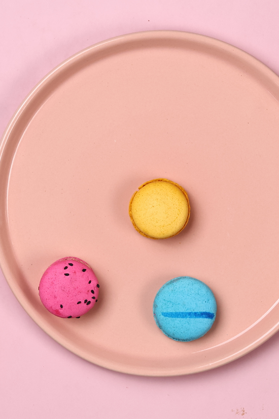 Yellow, pink, and blue macarons in pink platter