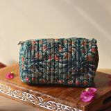 Green toiletry bag on wooden tray with flowers