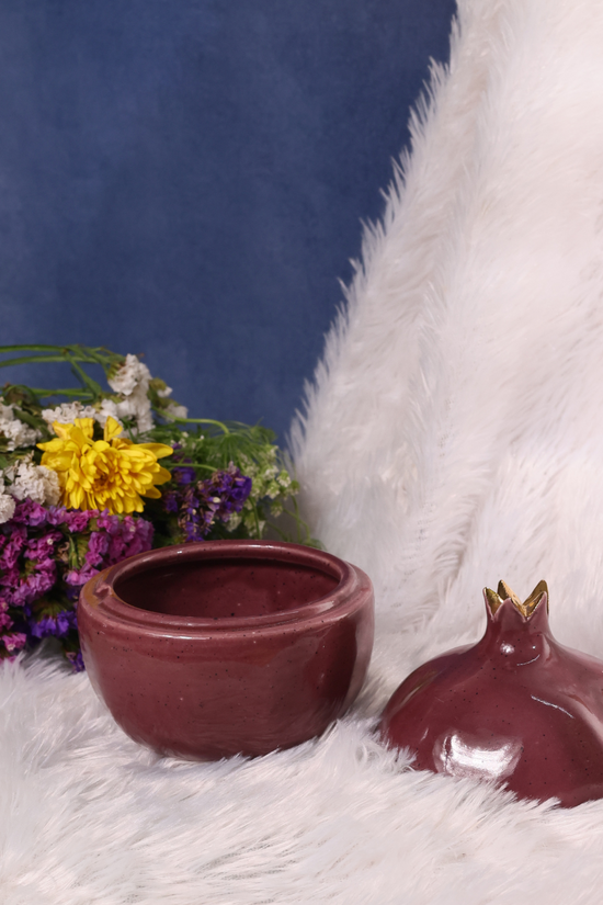 Open lid anar jar on a white cloth with flowers