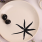 White plate with black leaf print on it