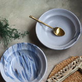 Two ceramic pasta plates with golden spoon