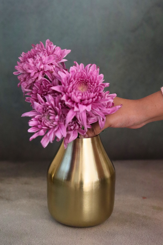 Brass glowing amber vase with flowers on hand