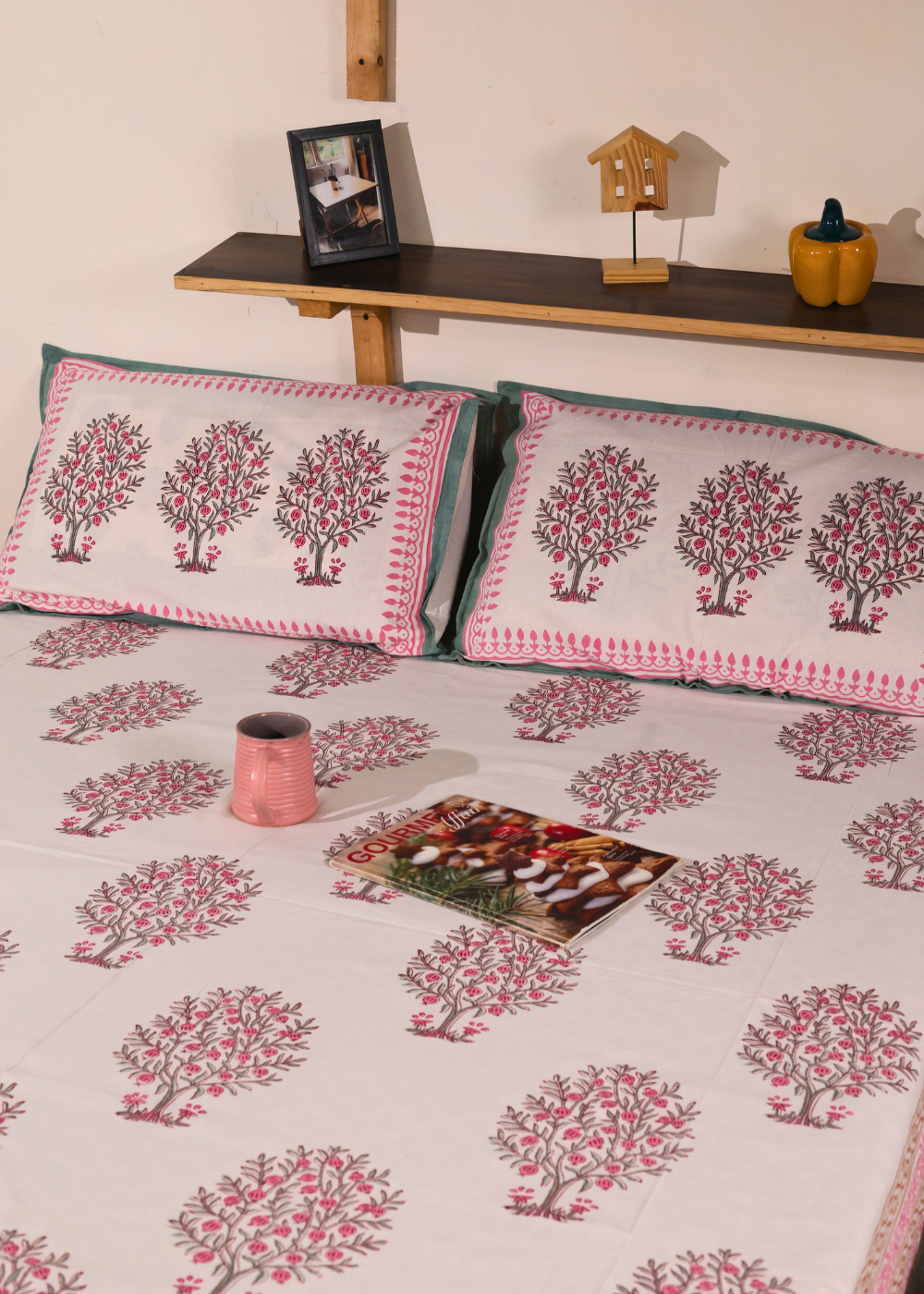 A mug and a magazine on a bed with beautiful bedsheet