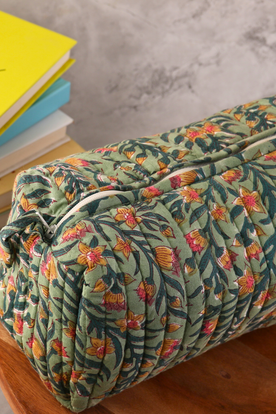 Block printed green toiletry bag on wooden surface