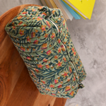 Green colored toiletry bag on wooden surface