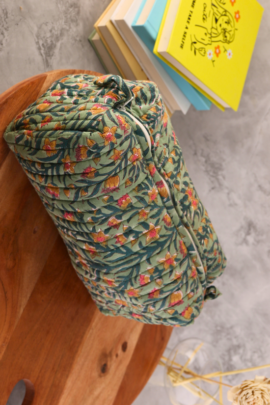 Green colored toiletry bag on wooden surface
