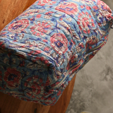 Block printed blue floral toiletry bag on a wooden surface