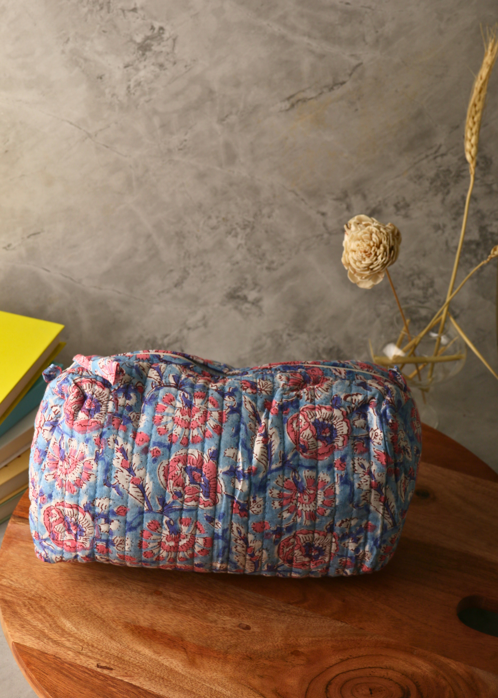 Block printed blue floral toiletry bag on a wooden surface