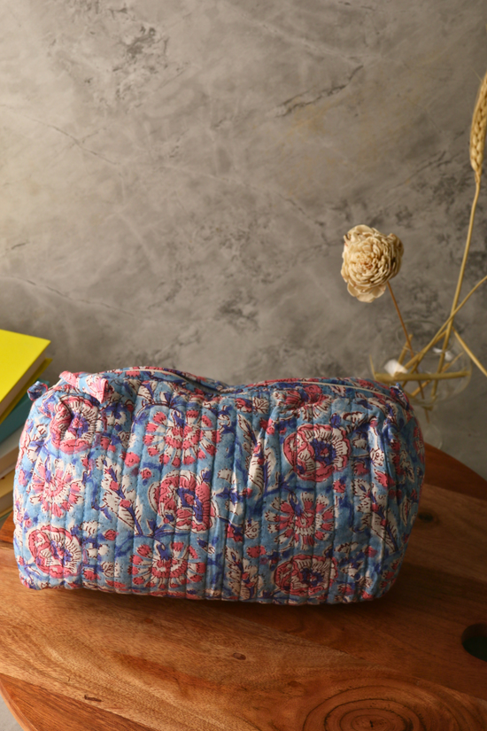 Block printed blue floral toiletry bag on a wooden surface