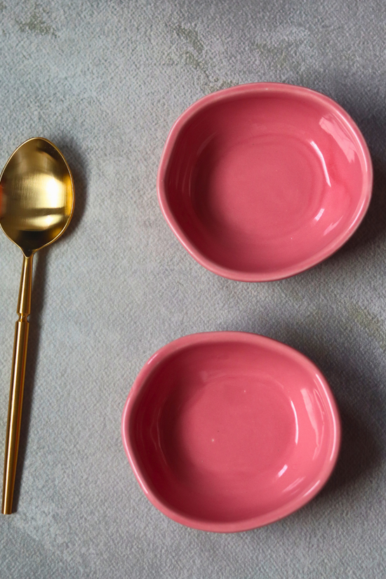Two pink nut bowls with cutlery