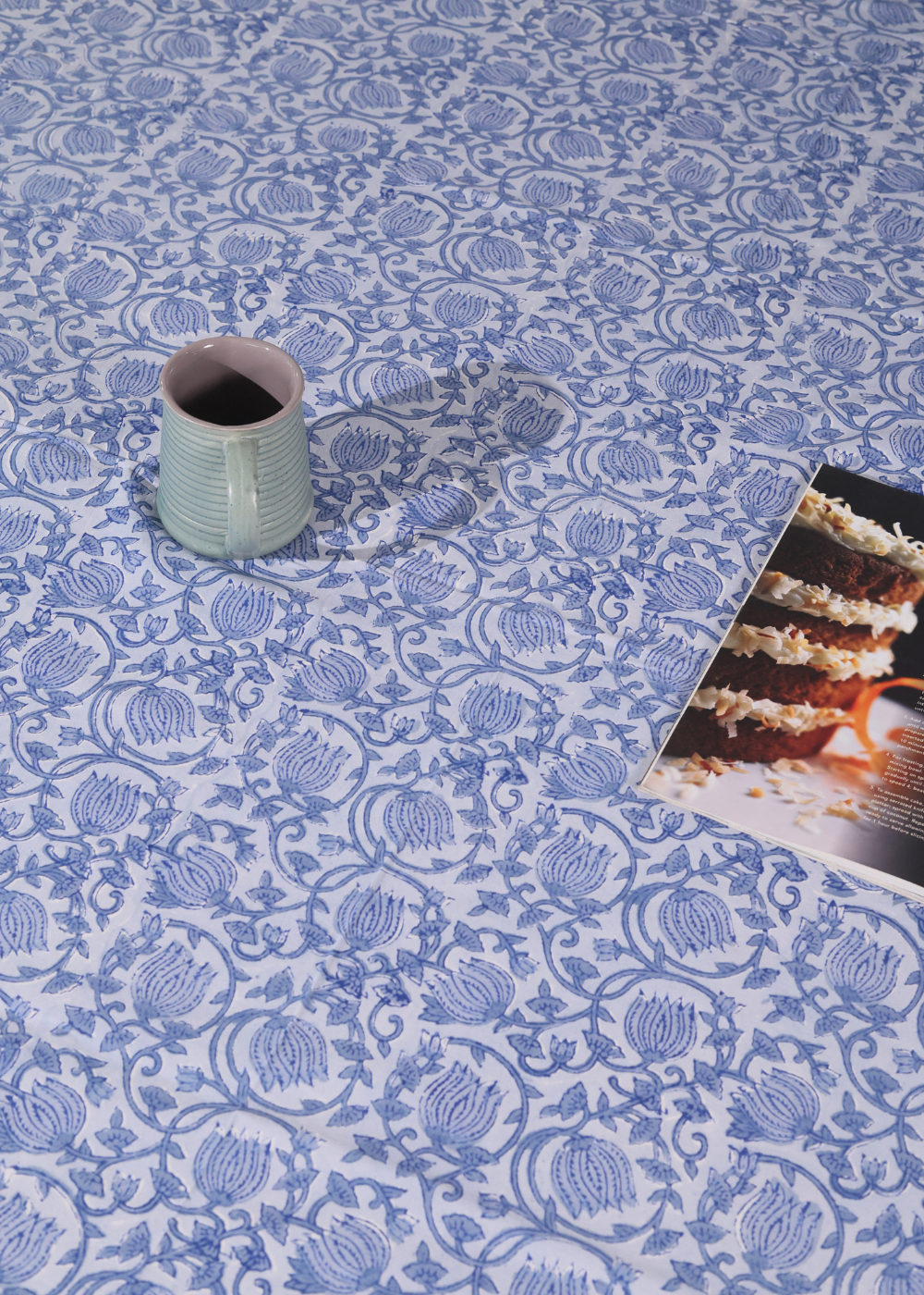 A mug and magazine on a blue lotus bedsheet