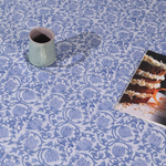 A mug and magazine on a blue lotus bedsheet