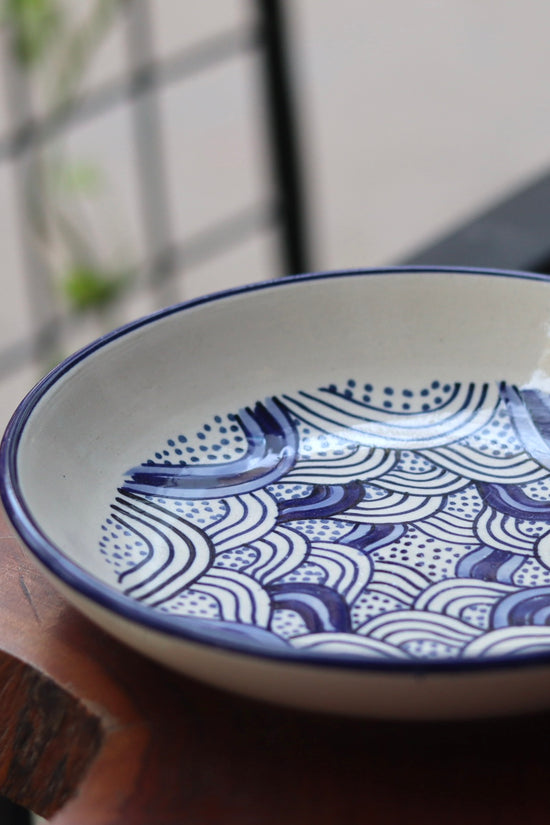 White & blue wavy pasta plate on wooden surface