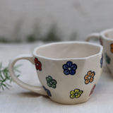 White coffee mug with flower designs on it 