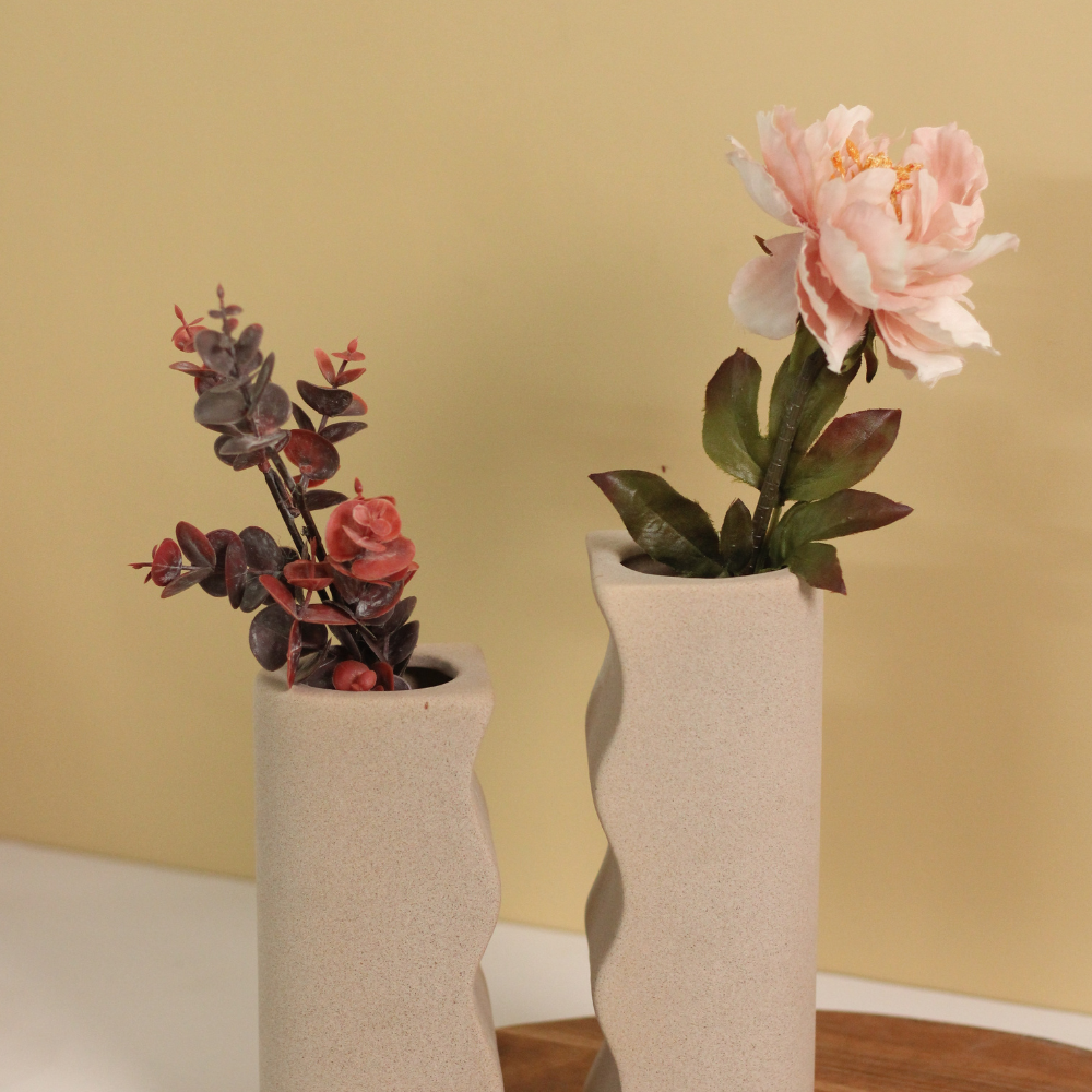 Two vases long and short with flowers on a wooden surface