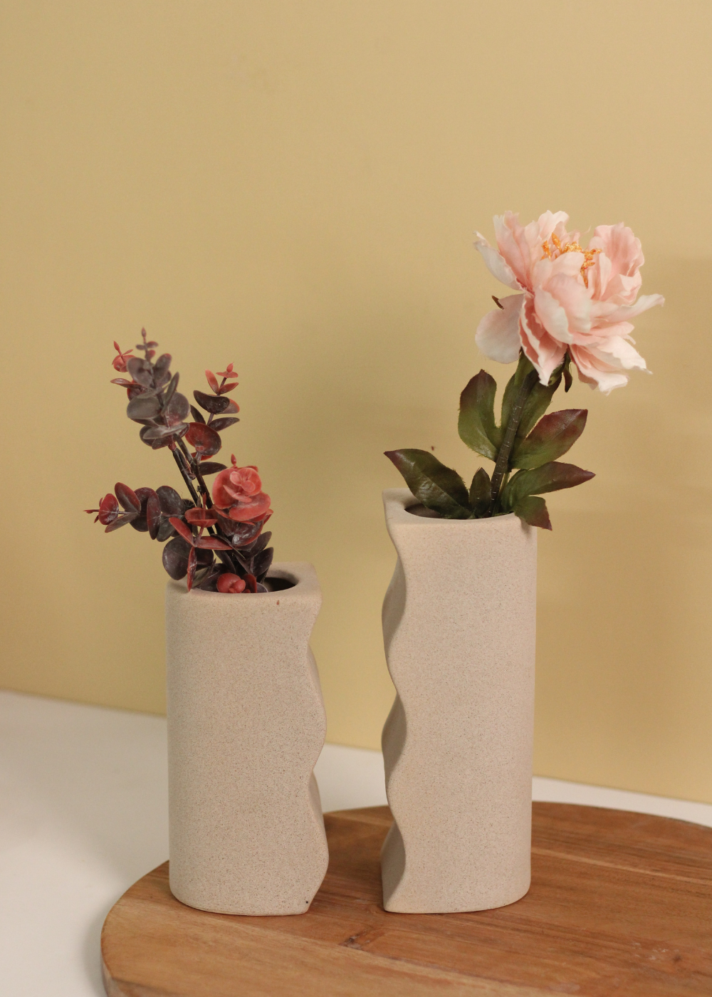 Two vases long and short with flowers on a wooden surface