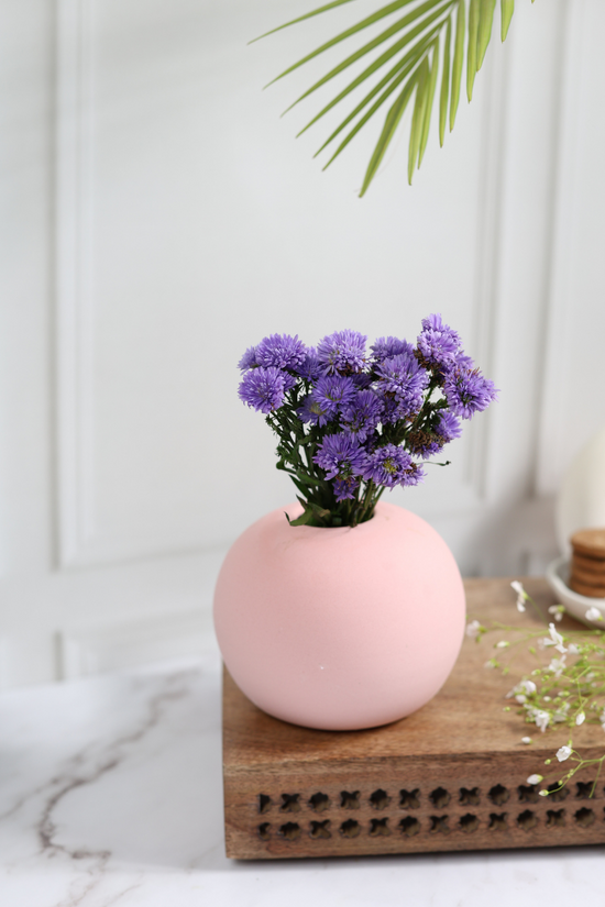 Pink color planter with lavender flowers on a wooden surface