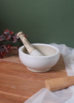 White mortar and pestle on a wooden surface