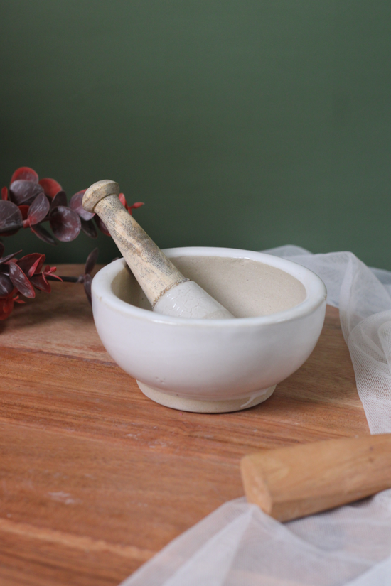 White mortar and pestle on a wooden surface
