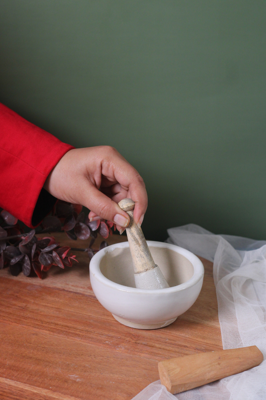 Someone holding pestle and mortar on a wooden surface
