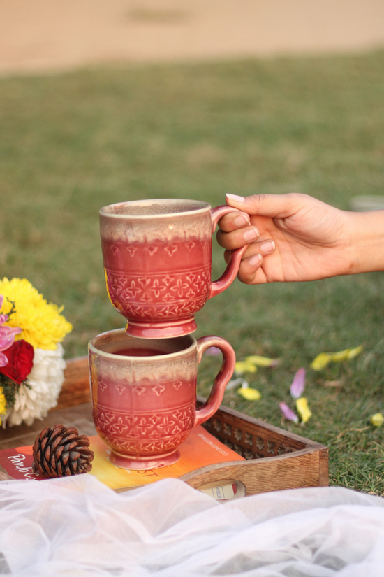 Two drinkware magenta coffee mugs in hand