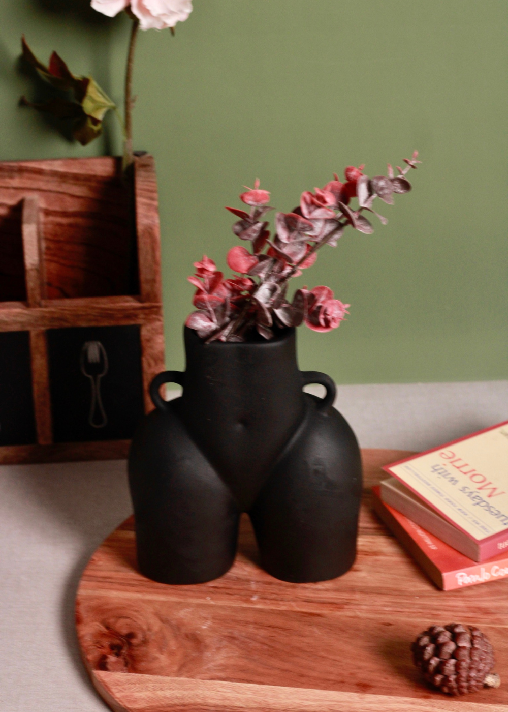 Black body vase with pink flowers on a wooden surface