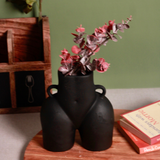 Black body vase with pink flowers on a wooden surface