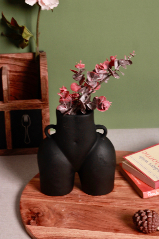 Black body vase with pink flowers on a wooden surface