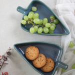 Two blue leaf bowls with bisciuts and grapes