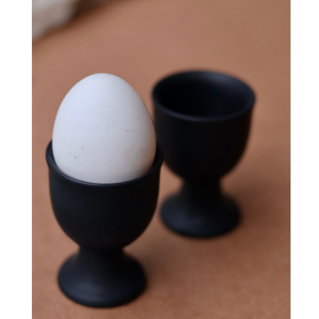 Two black egg holder one having egg