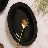 Black oval bowl with golden spoon