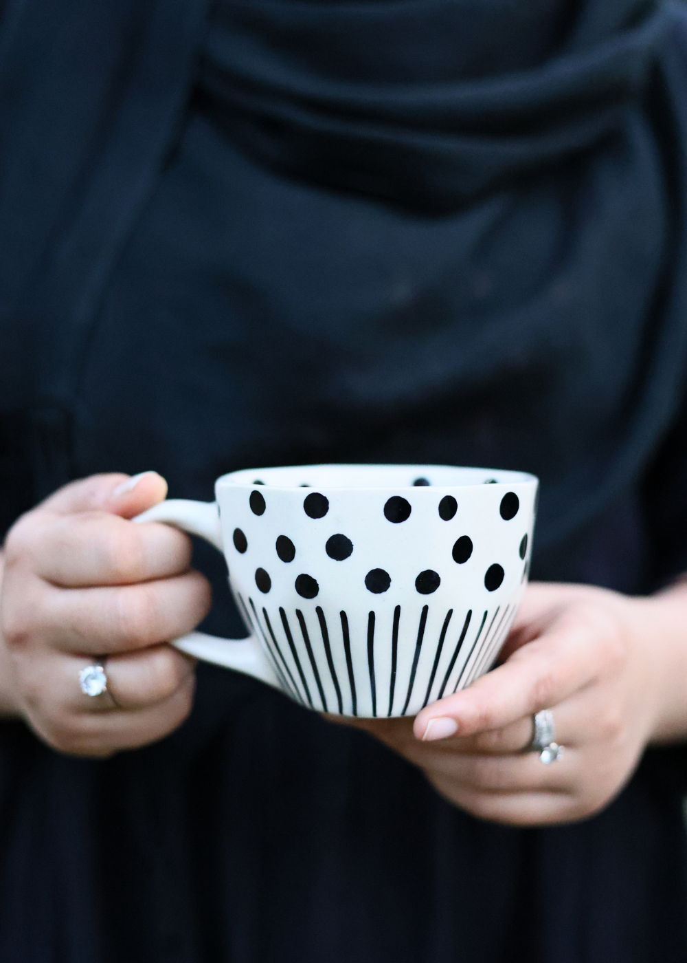 Black lines polka coffee mug in a hand