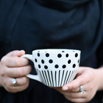 Black lines polka coffee mug in a hand