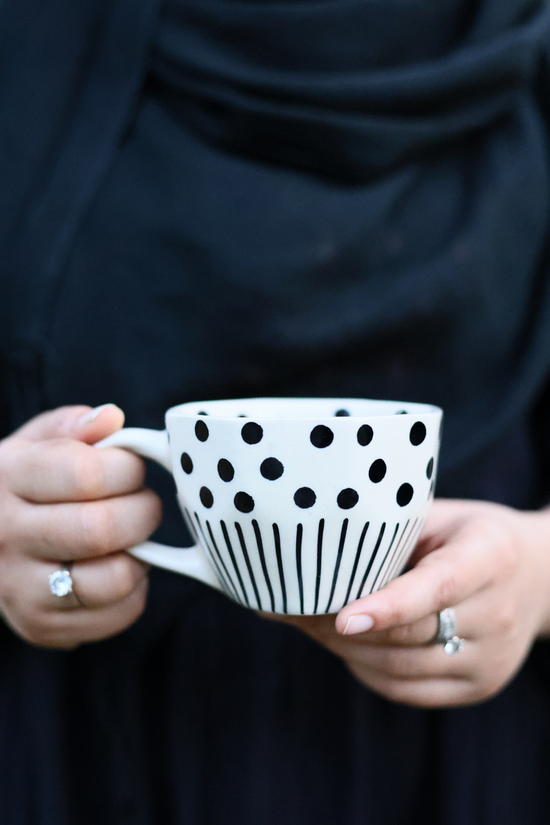Black lines polka coffee mug in a hand