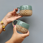 Brown and teal chai cups in hand