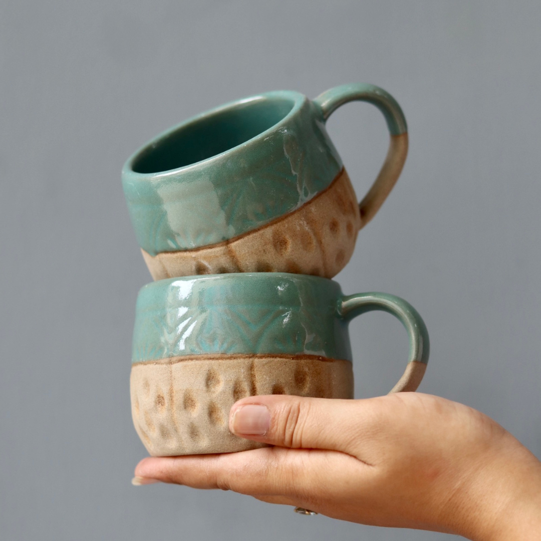 Brown & teal chai cups in hand