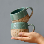 Brown & teal chai cups in hand