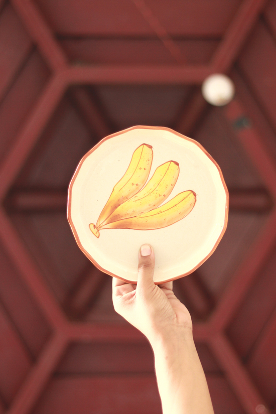 Someone holding a plate designed banana on it