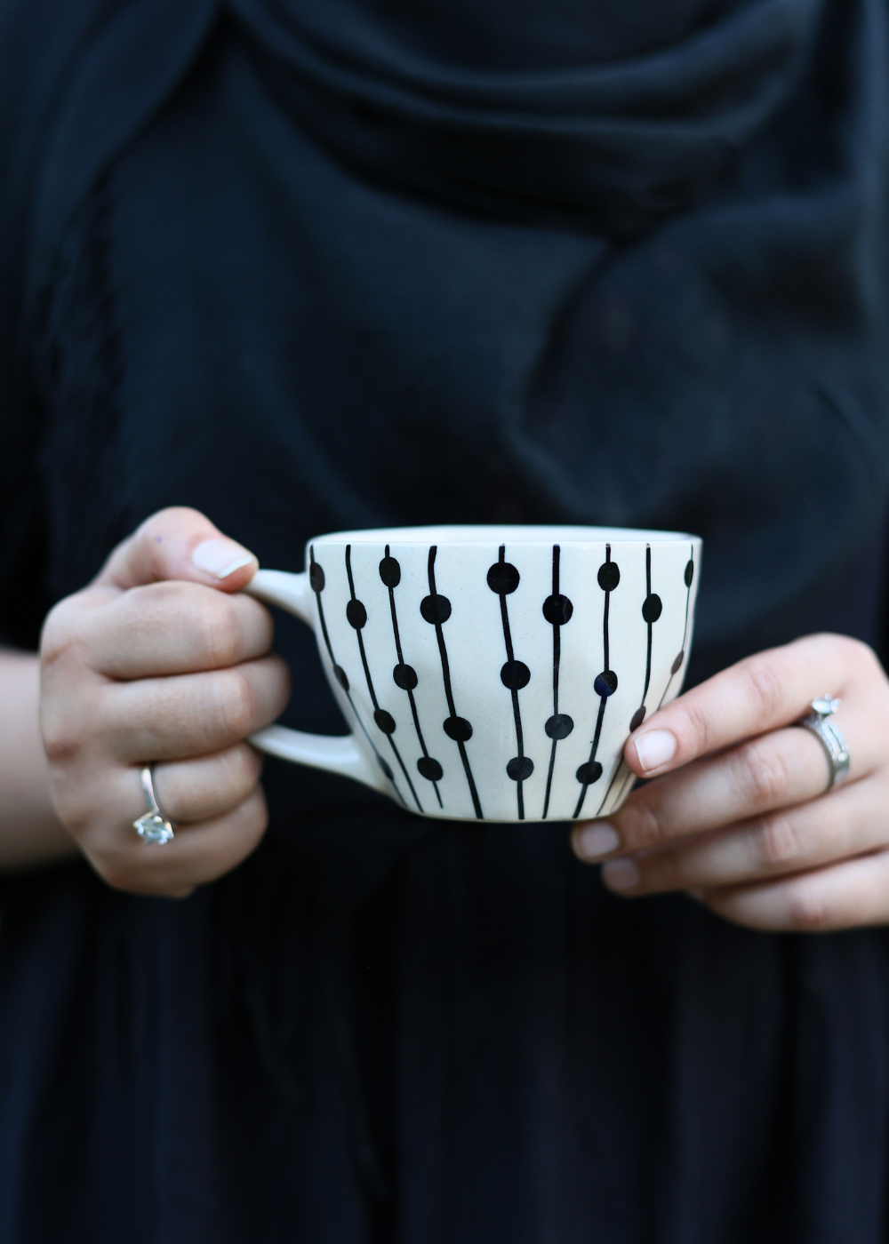 Handmade ceramic black dotted lines mug in a hand