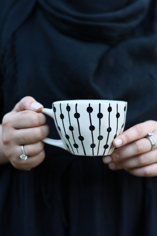 Handmade ceramic black dotted lines mug in a hand
