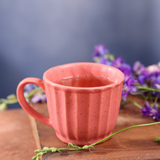 Pink tea cup with tea on a wooden surface