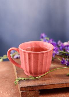 Pink tea cup with tea on a wooden surface