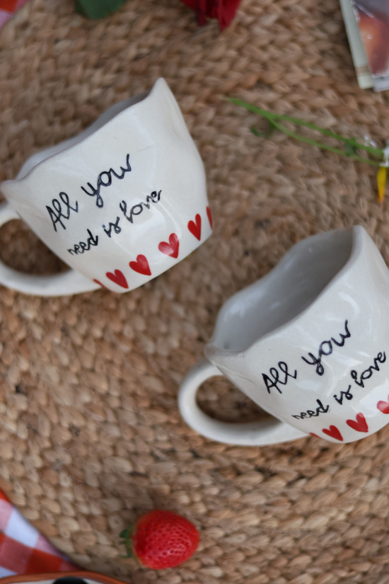 Two quoted coffee mugs and strawberry laying on a mat 