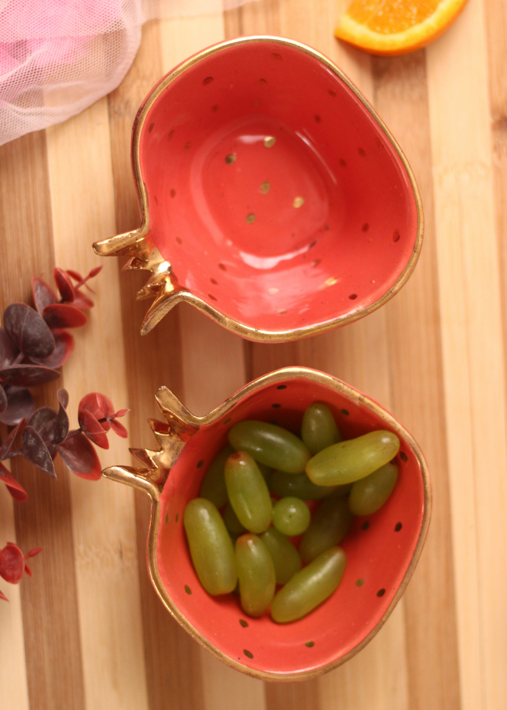 Two red anar bowls one has grapes