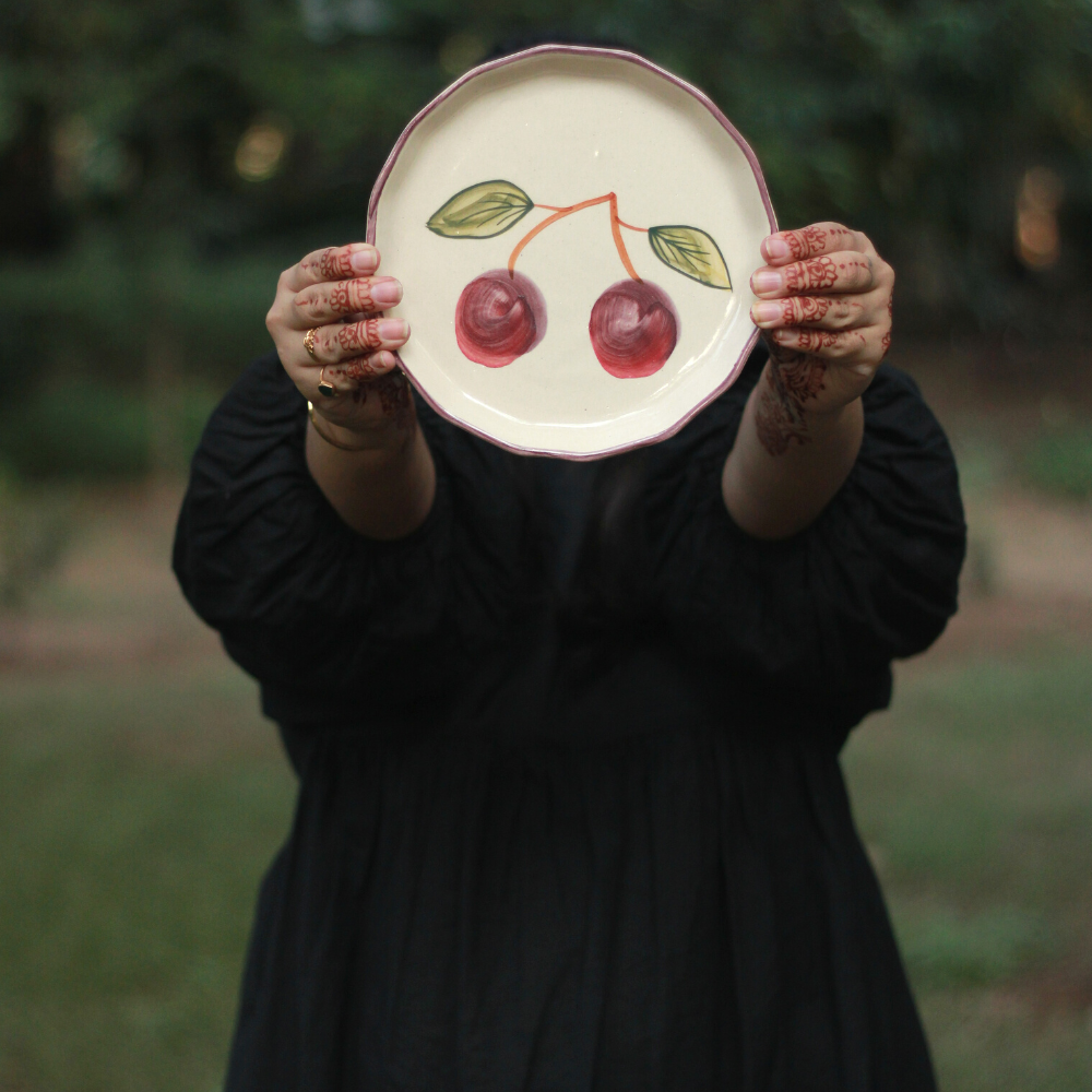 A girl is showing a cherry plate