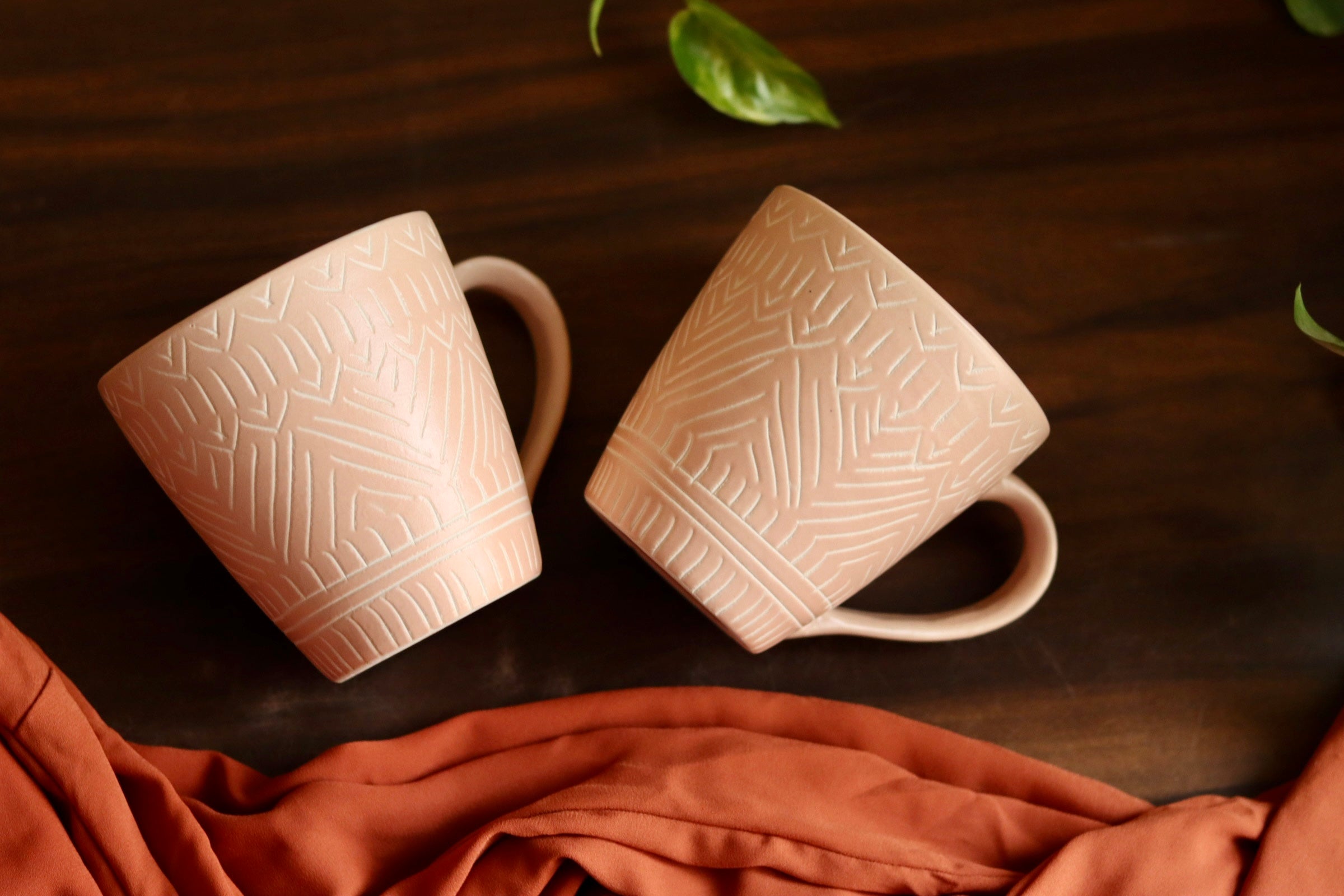 Blush pink carved coffee mug laying on wooden surface